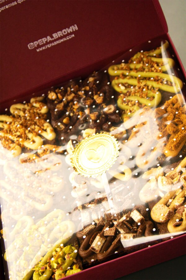 Caja de brownies artesanales de Pepa Brown con toppings variados, sellada con lámina transparente y etiqueta dorada