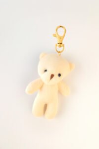 Llavero de peluche en tono crema con clip dorado, complemento ideal para cajas de regalo Pepa Brown.