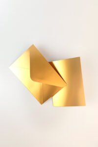 Sobre C6 dorado metalizado con tarjeta A6 a juego, sobre fondo blanco. Ideal para mensajes personalizados en regalos Pepa Brown.