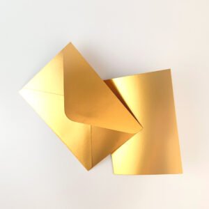 Sobre C6 dorado metalizado con tarjeta A6 a juego, sobre fondo blanco. Ideal para mensajes personalizados en regalos Pepa Brown.